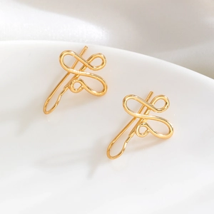 Detailed view of elegant gold ribbon knot earrings on white ceramic and fabric