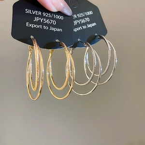 Detail of 18k gold plated double-layer hoop earrings showing matte and mirror texture
