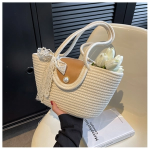 Detail of straw woven tote with brown leather flap, pearl button and white lace bow