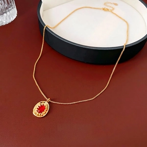 Vintage gold necklace with oval red gemstone pendant and engraved details on red surface