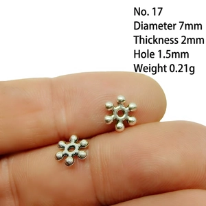 Macro shot of 7mm snowflake-shaped silver spacer bead with technical dimensions and size