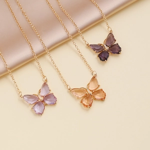 Detailed view of colorful zircon butterfly necklaces on soft beige silk fabric