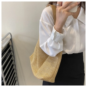 Close-up of khaki woven straw shoulder bag with elegant faux leather straps on a model