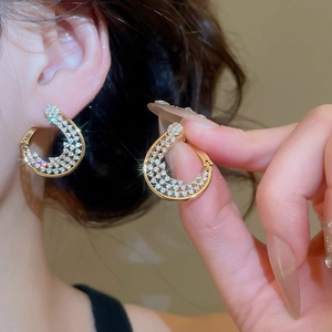 Gros plan de boucles d'oreilles en C plaquées or 18K serties de zircons blancs