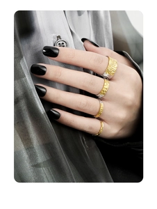 Detailed view of layered silver and gold rings with a natural lava crinkle texture on fingers