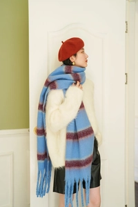 Detail of blue and red striped scarf with thick fringe paired with a stylish red beret
