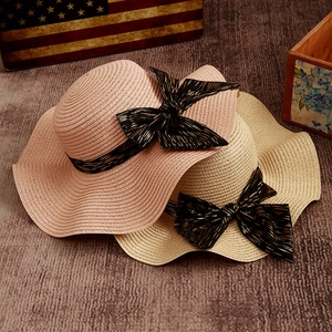 Women's summer straw sun hat with wavy brim and black bow in pink and beige