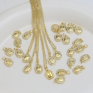 Octagonal 18k gold plated letter pendants with cubic zirconia on a white plate