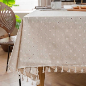 Close-up of linen tablecloth featuring daisy patterns and beige tassel edge details