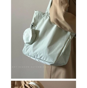 Close-up of light green nylon tote bag featuring a detachable round coin purse detail