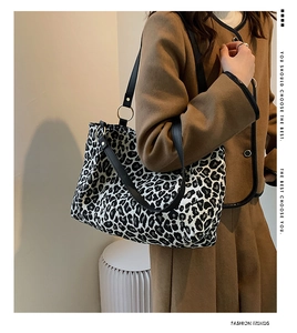 Detail view of leopard print canvas tote bag with gold rings and black leather straps