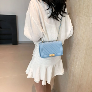 Detail of light blue quilted leather handbag with gold metal lock and chain strap