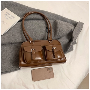 Detail view of brown vintage pillow bag with dual front pockets and silver buckle accents