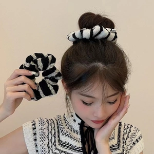 Detail of a fluffy black and white striped tweed scrunchie worn on a model's ponytail