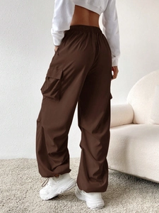 Detail of loose deep brown cargo pants with elastic waist and flap pockets on back