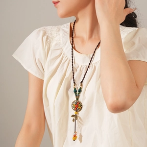 Close-up of ethnic ceramic beaded necklace with leaf pendant on a brown woven rope