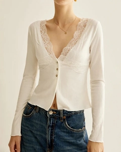 Detail of white slim-fit V-neck top featuring delicate lace trim and ribbed fabric texture