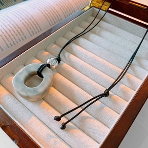 Irregular faux stone pendant with black cord on velvet lining in a wooden box