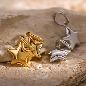 Créoles dorées et argentées avec pendentifs étoiles 3D sur un support en pierre naturelle