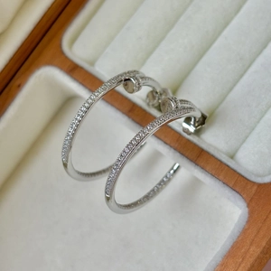 Dettaglio macro di orecchini a chiodo a forma di C in argento S925 con zirconi su velluto bianco