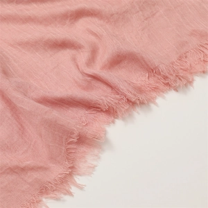 Detail showing the pink cotton linen fabric texture and delicate fringe edge of the scarf