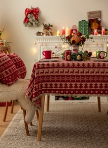 Detail of red Christmas tablecloth with white deer patterns and delicate lace edge