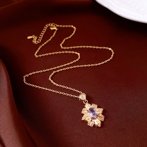 Close-up of a 14k gold plated rhombic pendant with purple gemstone and crystals