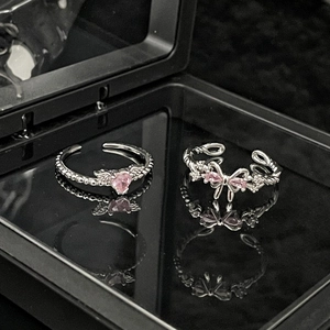 Detailed shot of pink heart and butterfly rings with sparkling stones on dark surface