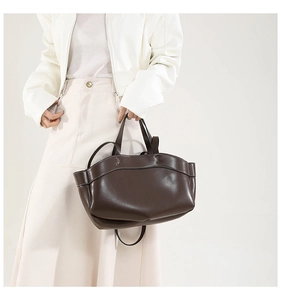 Dettaglio della borsa tote in pelle marrone scuro con cuciture a H e manici arrotondati
