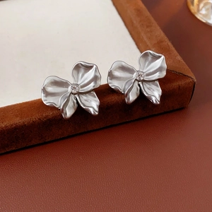 Macro shot of silver pleated bow earrings with a single sparkling cubic zirconia center