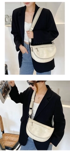 Detailed street style shot of cream PU leather half-moon bag with adjustable wide strap