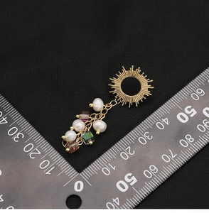 Macro detail of natural pearl drop earrings with measurement scale on black background