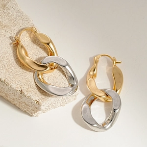 Detail of gold and silver interlocking geometric loop earrings on stone background