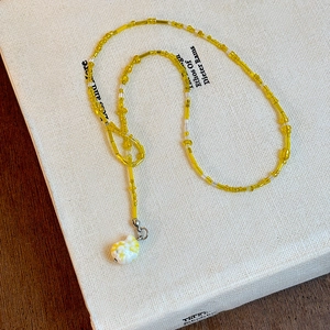 Colorful yellow seed bead necklace with a white conch shell pendant for beach vacations