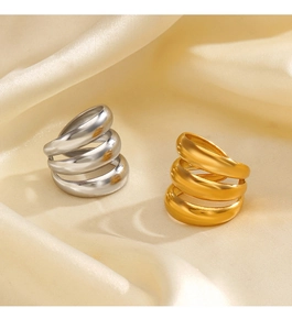 Dettaglio di anelli a tre strati ondulati in oro e argento su un tessuto di seta crema