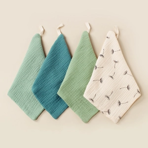 Close-up of four-piece double muslin cotton baby towels with hanging loops and soft texture
