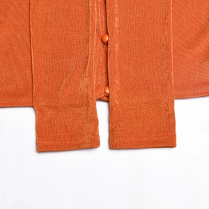 Détail du cardigan court en velours côtelé orange avec texture côtelée et boutons