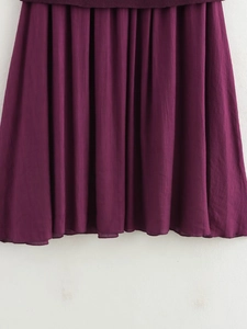 Detailed close-up of dark purple pleated fabric showing fine texture and vertical drape