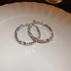 Vue détaillée de créoles argentées serties de zircons sur une assiette blanche