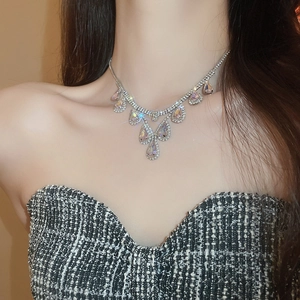 Close-up of model wearing silver teardrop pendant necklace with clear and iridescent crystals