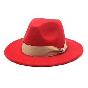 Detail eines roten Wollfilz-Fedoras mit khakifarbenem Band und funkelnder Strassschnalle