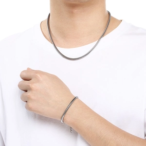 Close-up of polished silver stainless steel snake chain necklace and bracelet on model