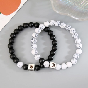 Detail view of sun and moon charm beaded bracelets in matte black and white marble stone