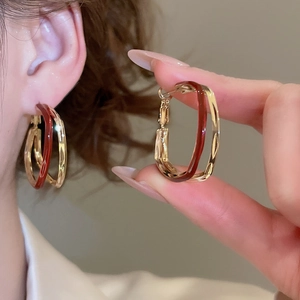 Detailed view of double hoop geometric C-shaped earrings with red enamel and gold finish