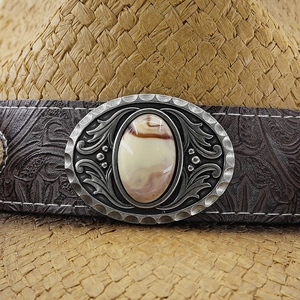 Detail of western cowboy straw hat featuring embossed leather band and vintage metal buckle