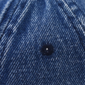 Detailed macro view of washed denim fabric with stitched ventilation eyelet and twill texture