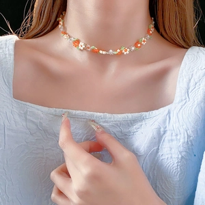 Close-up of colorful flower beaded necklace worn on neck with orange and green petals
