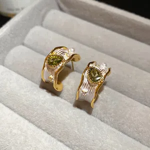 Vintage C-shaped gold earrings with green gemstone and small pearls on velvet display