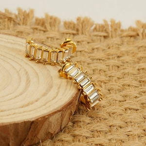 Macro shot of gold U-shaped earrings featuring channel-set baguette cut clear zircons