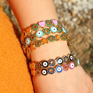 Gold chain bracelet with colorful zircon flowers, evil eyes and heart charm on wrist